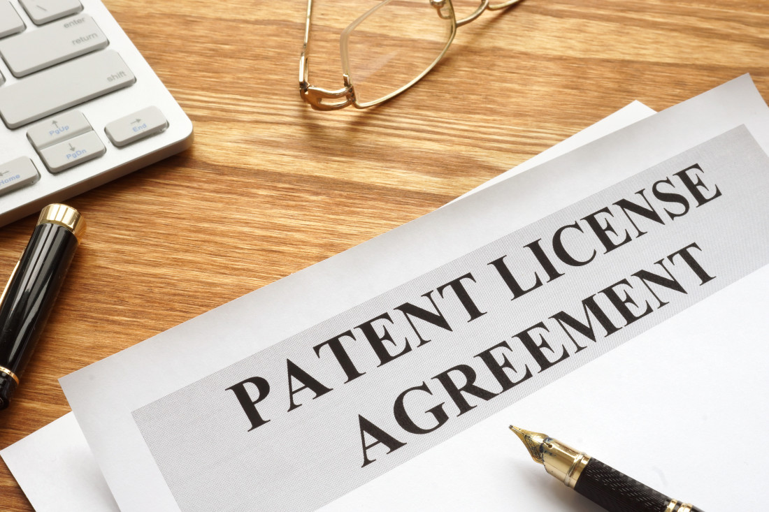 Patent License Agreement Heading with pens, eyeglasses and a calculator on a table